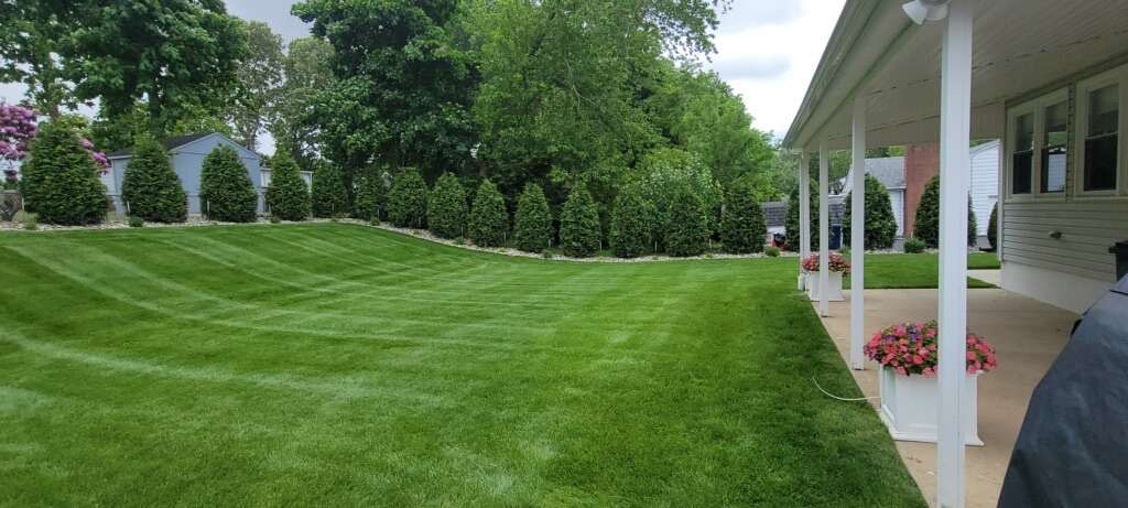 Freshly mowed lawn with mower stripes along a covered porch
