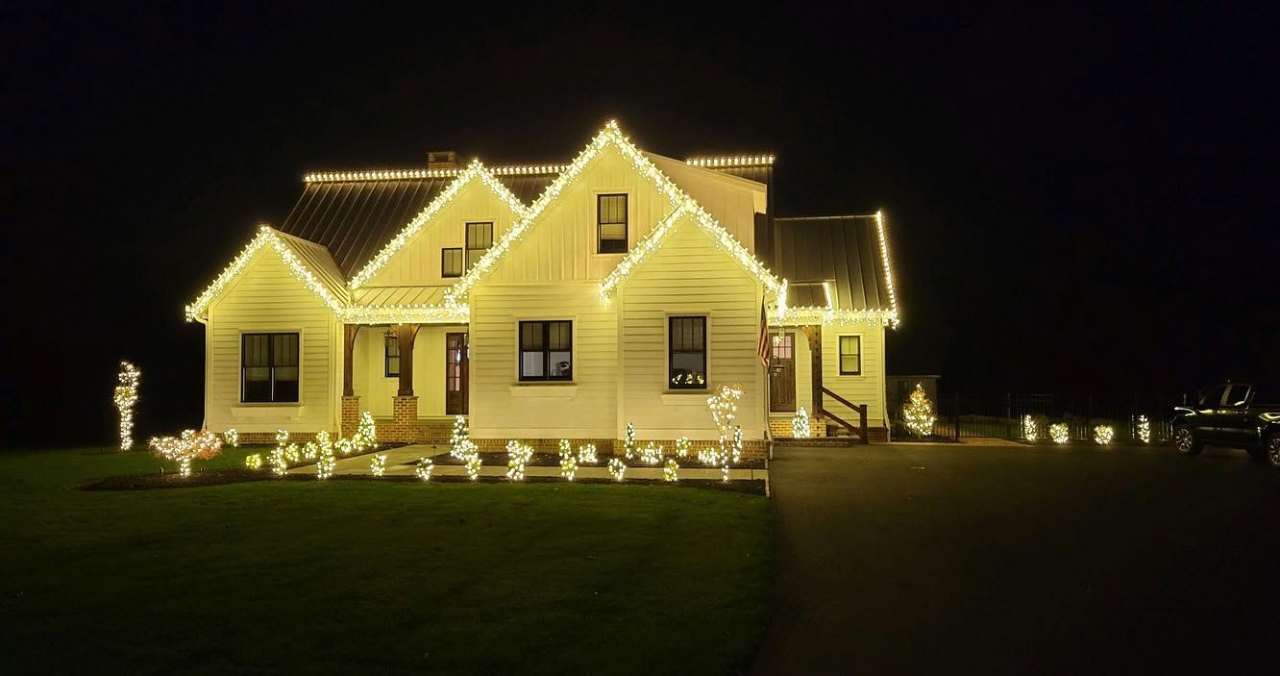 Farmhouse outlined in warm white holiday lighting