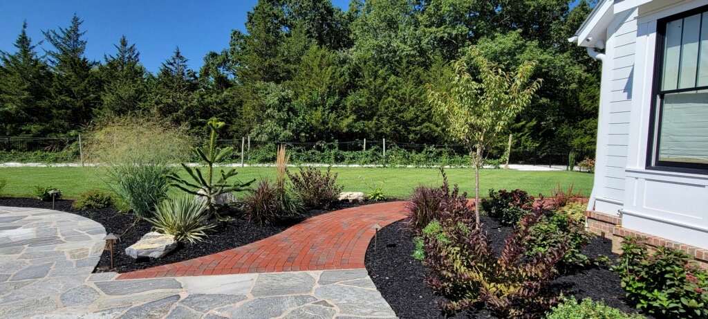Shaped shrubs, grasses and fresh beds along a flagstone walk