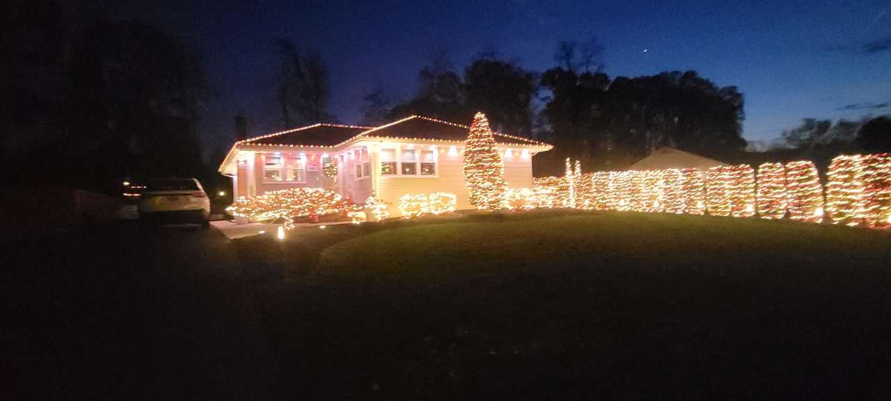 Ranch home outlined in holiday lights at dusk