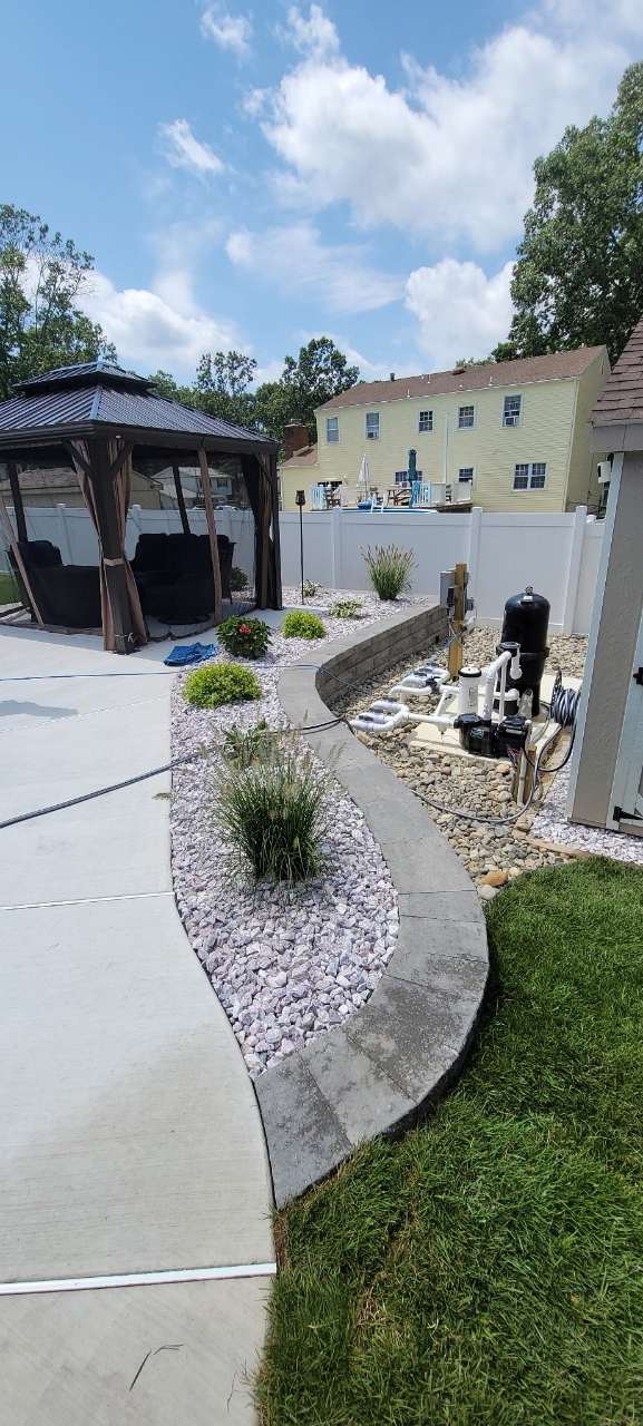 Concrete walkway between fresh lawn and a rock bed