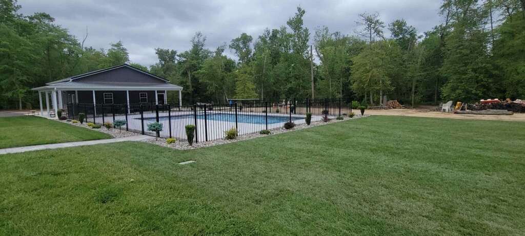 Wide irrigated lawn running back to a pool and gazebo
