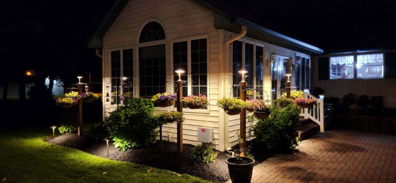 Path lights along a porch and planted beds at night