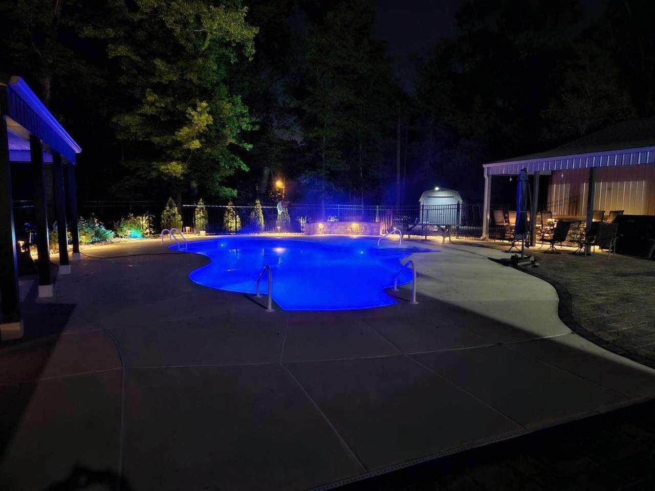 Pool and pavilion lit at night with landscape lighting