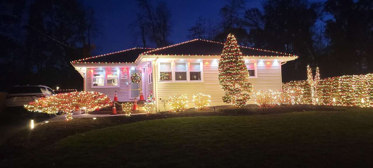 Ranch home and yard tree in warm holiday lights