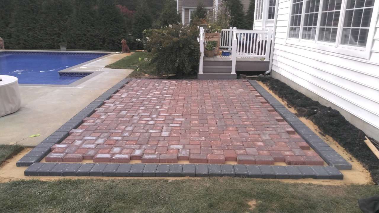 Finished brick paver patio with charcoal border, pool and deck beyond