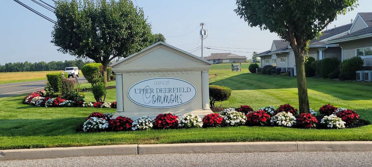 Red and white annuals around a community entrance sign