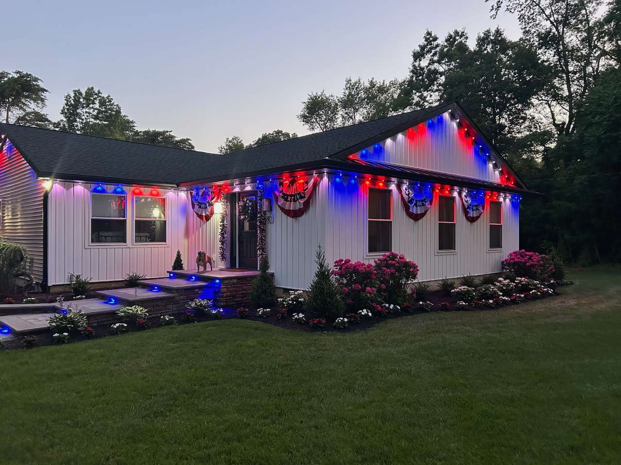 Ranch home with red, white and blue roofline lighting and blue path lights at dusk