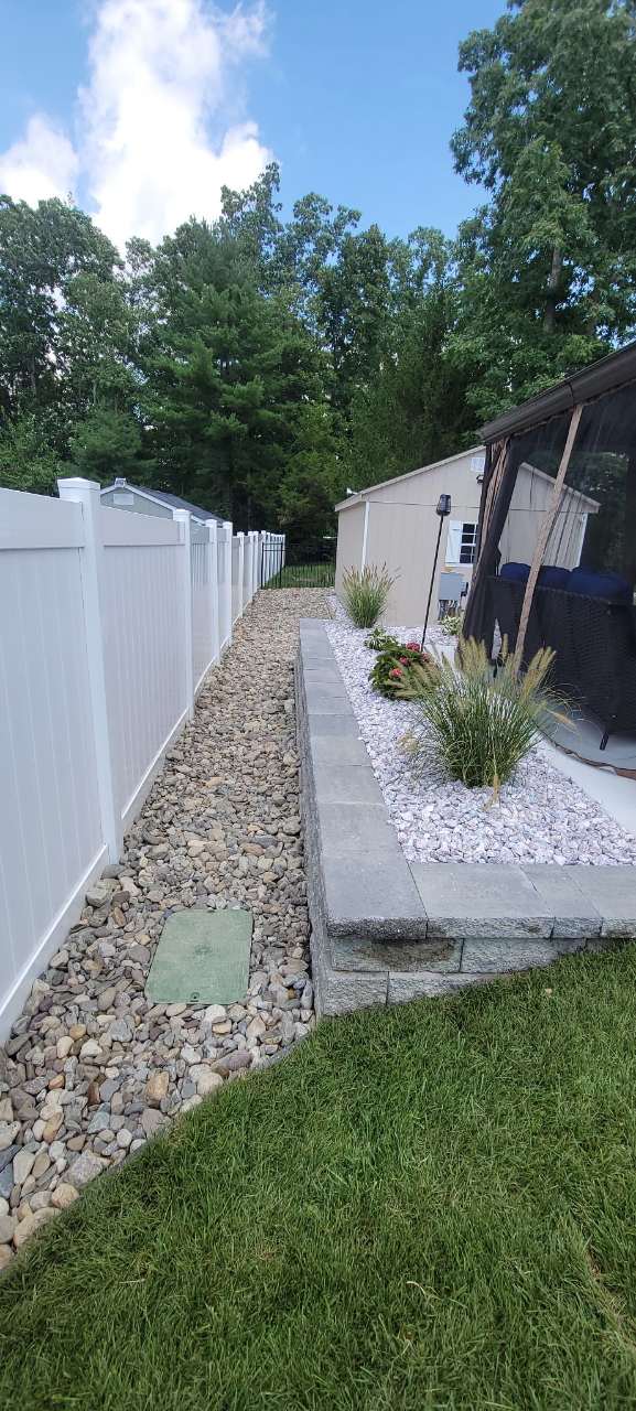 River-rock bed running beside a walkway and fence