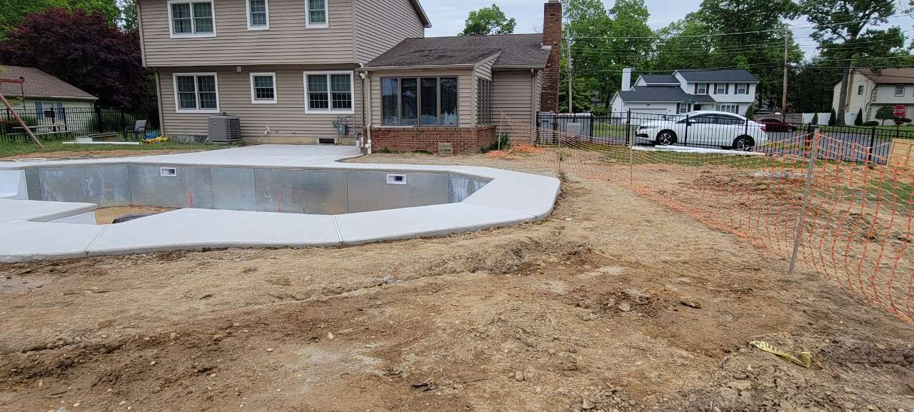 Bare graded dirt around a new pool shell before the lawn install